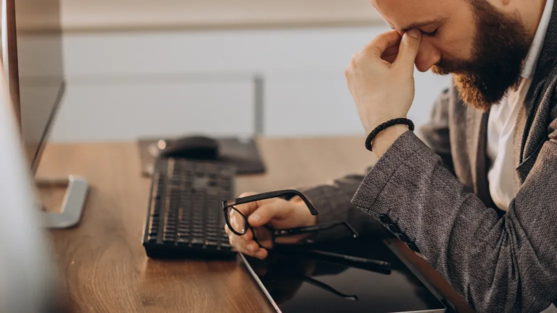 Empresário com as mãos na cabeça após falha de energia que desligou os computadores da empresa, ilustrando o impacto de problemas na rede elétrica no ambiente empresarial.